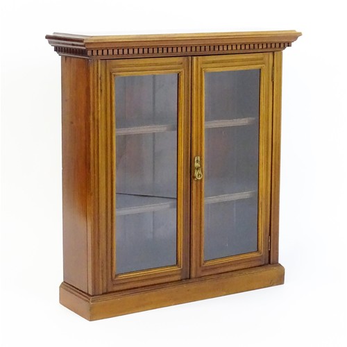 1367 - An early 20thC walnut bookcase with a moulded cornice above a dentil craved frieze with two glazed d... 