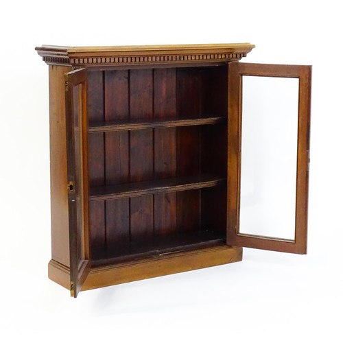 1367 - An early 20thC walnut bookcase with a moulded cornice above a dentil craved frieze with two glazed d... 