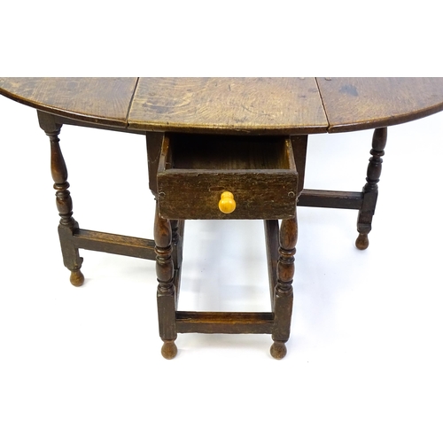 1332 - An early 18thC oak drop leaf table with a small drawer to end, the two leaves opening to form and ov... 