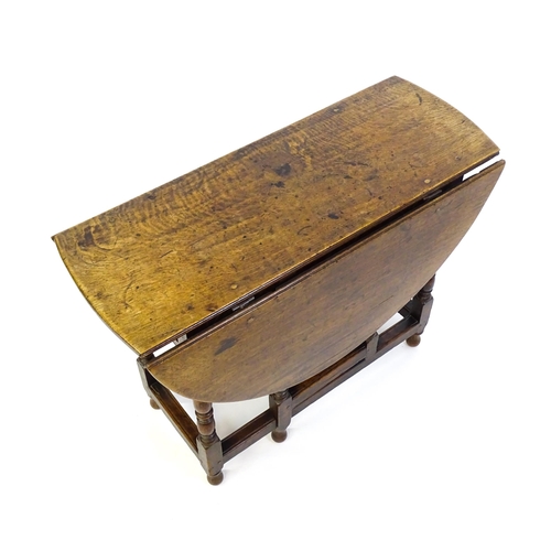 1332 - An early 18thC oak drop leaf table with a small drawer to end, the two leaves opening to form and ov... 