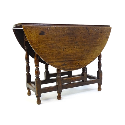 1332 - An early 18thC oak drop leaf table with a small drawer to end, the two leaves opening to form and ov... 