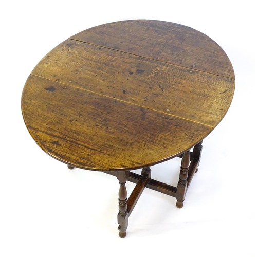 1332 - An early 18thC oak drop leaf table with a small drawer to end, the two leaves opening to form and ov... 