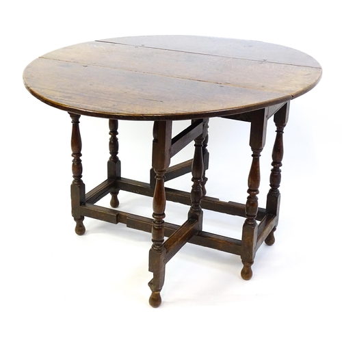 1332 - An early 18thC oak drop leaf table with a small drawer to end, the two leaves opening to form and ov... 