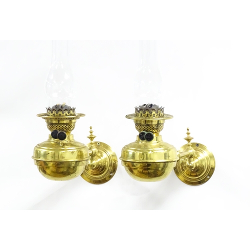 1313 - A pair of early 20thC oil lamps, the adjustable wall mounts supporting duplex burners, each approx 1... 