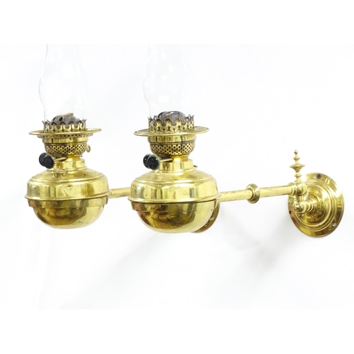 1313 - A pair of early 20thC oil lamps, the adjustable wall mounts supporting duplex burners, each approx 1... 