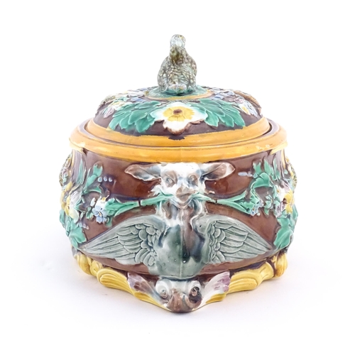 76 - A Victorian majolica game pie dish and cover, the body decorated in relief with birds, flowers and f... 