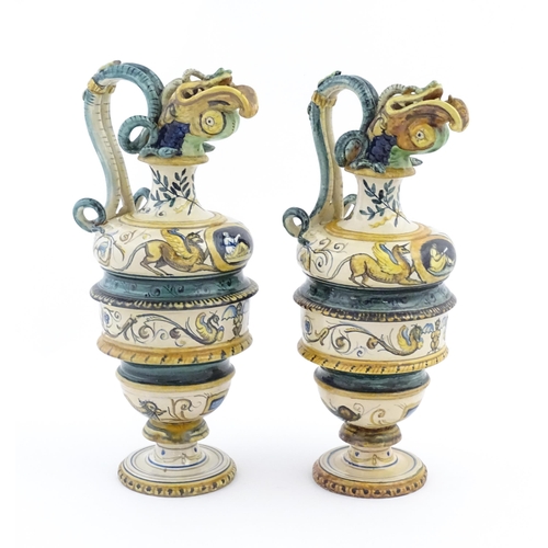 209 - A pair of Italian maiolica wine ewers with fish head spouts, scrolling handles and relief mask detai... 