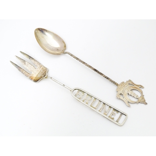 460 - A white metal souvenir fork titled Brunei to handle. Together with a white metal teaspoon also title... 