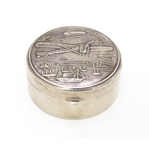 304 - A .925 silver pill box of circular form decorated to lid with images of an aeroplane, airship, boats... 