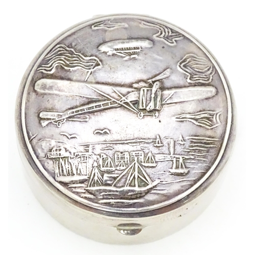 304 - A .925 silver pill box of circular form decorated to lid with images of an aeroplane, airship, boats... 