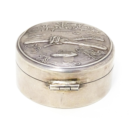 304 - A .925 silver pill box of circular form decorated to lid with images of an aeroplane, airship, boats... 