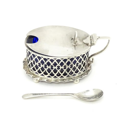 391 - A silver mustard pot of oval form with pierced detail and blue glass liner, hallmarked London 1902.T... 