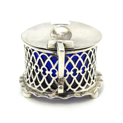 391 - A silver mustard pot of oval form with pierced detail and blue glass liner, hallmarked London 1902.T... 