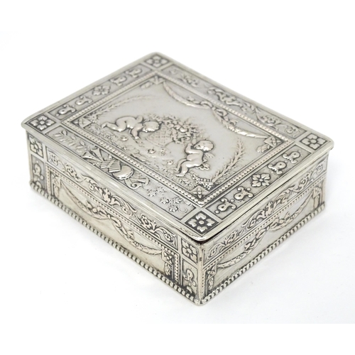 435 - A Continental silver box decorated with cherubs, floral and swag detail and opening to reveal a red ... 