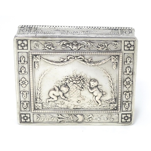 435 - A Continental silver box decorated with cherubs, floral and swag detail and opening to reveal a red ... 