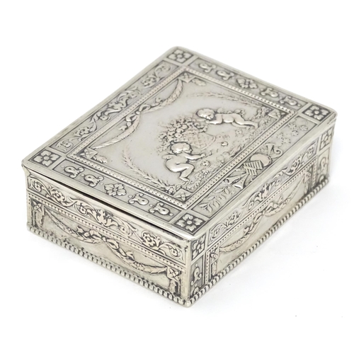 435 - A Continental silver box decorated with cherubs, floral and swag detail and opening to reveal a red ... 