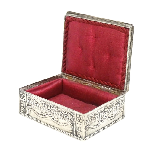 435 - A Continental silver box decorated with cherubs, floral and swag detail and opening to reveal a red ... 