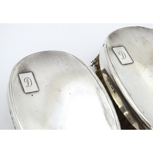 497 - A pair of Art Deco silver backed hair brushes of oval form with engine turned decoration, hallmarked... 