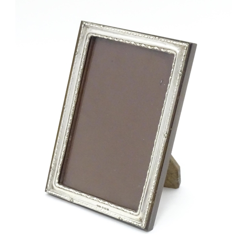 519 - An easel photograph frame with silver surround hallmarked Birmingham 1954, maker W. I. Broadway & Co... 