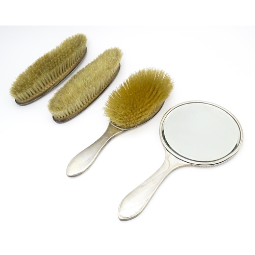 537 - A silver four piece dressing table set comprising three brushes and a hand mirror with banded engine... 