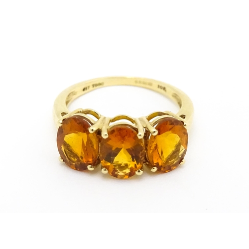 569 - A 9ct gold ring set with three citrine. Ring size approx. L 1/2