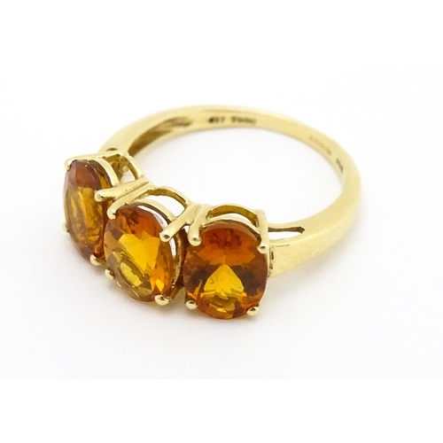 569 - A 9ct gold ring set with three citrine. Ring size approx. L 1/2