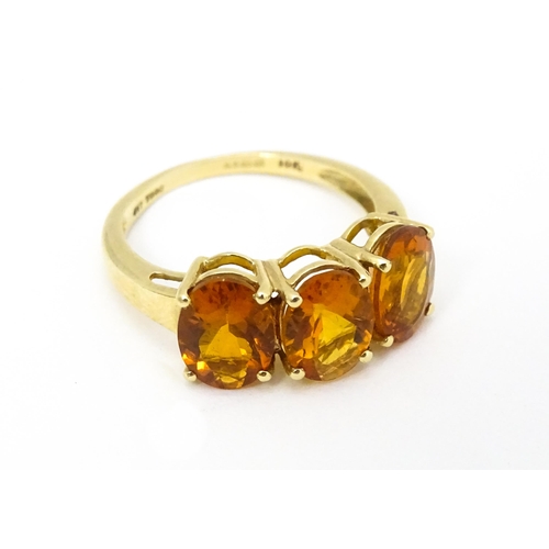 569 - A 9ct gold ring set with three citrine. Ring size approx. L 1/2