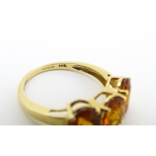 569 - A 9ct gold ring set with three citrine. Ring size approx. L 1/2