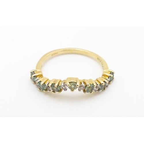 571 - A 9ct gold ring set with green and white stones. Ring size approx. L