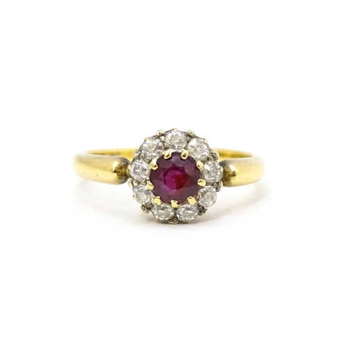 576 - An 18ct gold ring set with central ruby bordered by diamonds. Ring size approx. O 1/2