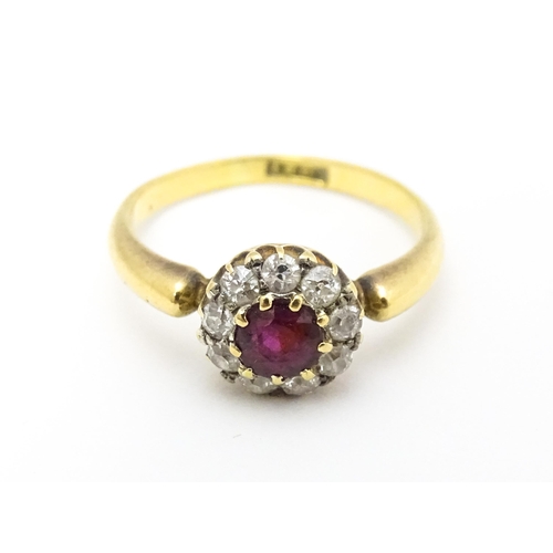 576 - An 18ct gold ring set with central ruby bordered by diamonds. Ring size approx. O 1/2