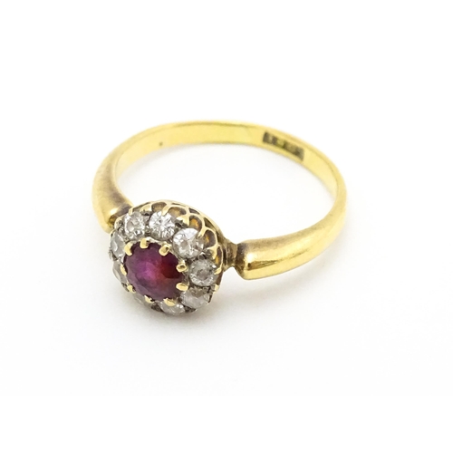 576 - An 18ct gold ring set with central ruby bordered by diamonds. Ring size approx. O 1/2