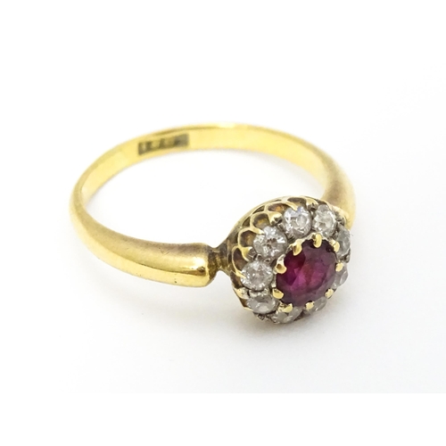 576 - An 18ct gold ring set with central ruby bordered by diamonds. Ring size approx. O 1/2