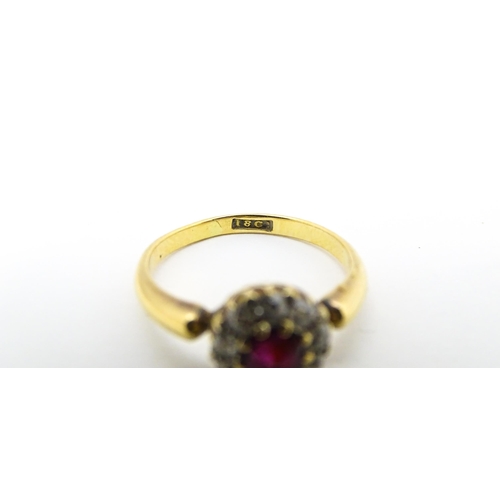 576 - An 18ct gold ring set with central ruby bordered by diamonds. Ring size approx. O 1/2