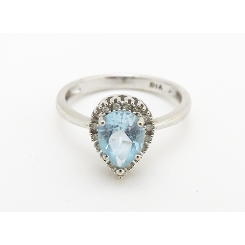 580 - A 9ct white gold ring set with central blue topaz coloured stone bordered by diamonds. Ring size app... 