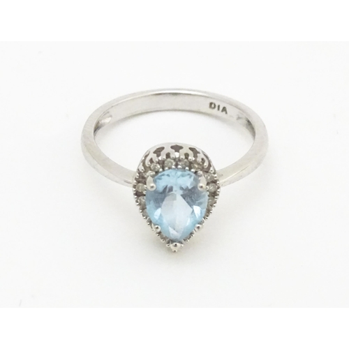 580 - A 9ct white gold ring set with central blue topaz coloured stone bordered by diamonds. Ring size app... 