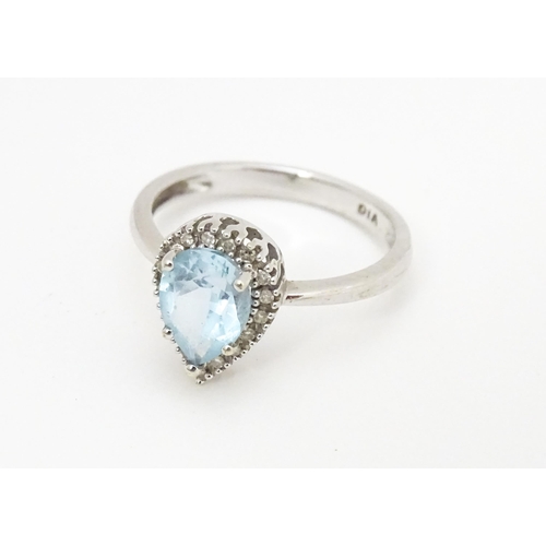 580 - A 9ct white gold ring set with central blue topaz coloured stone bordered by diamonds. Ring size app... 