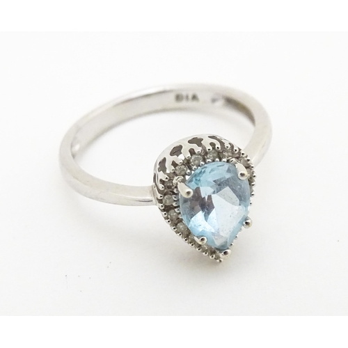 580 - A 9ct white gold ring set with central blue topaz coloured stone bordered by diamonds. Ring size app... 