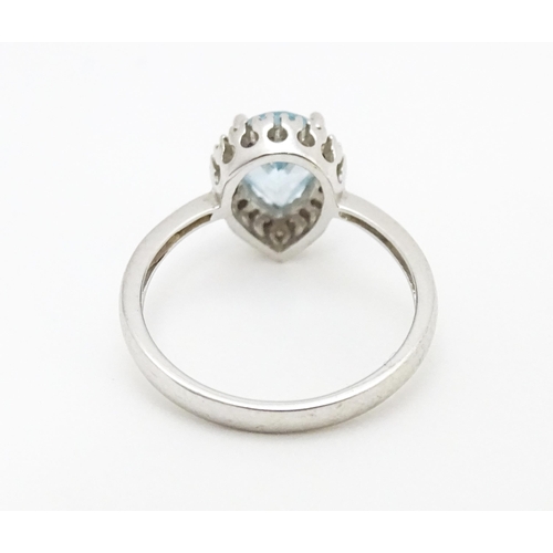 580 - A 9ct white gold ring set with central blue topaz coloured stone bordered by diamonds. Ring size app... 