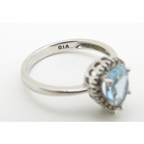 580 - A 9ct white gold ring set with central blue topaz coloured stone bordered by diamonds. Ring size app... 