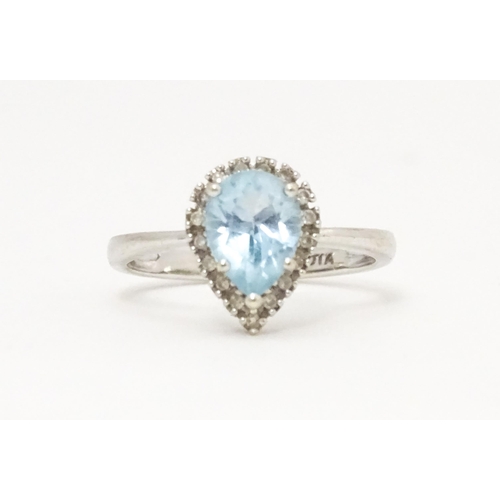 580 - A 9ct white gold ring set with central blue topaz coloured stone bordered by diamonds. Ring size app... 