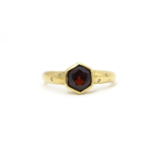 585 - A 9ct gold ring set with central hexagonal garnet flanked by two diamonds to each shoulder Ring size... 