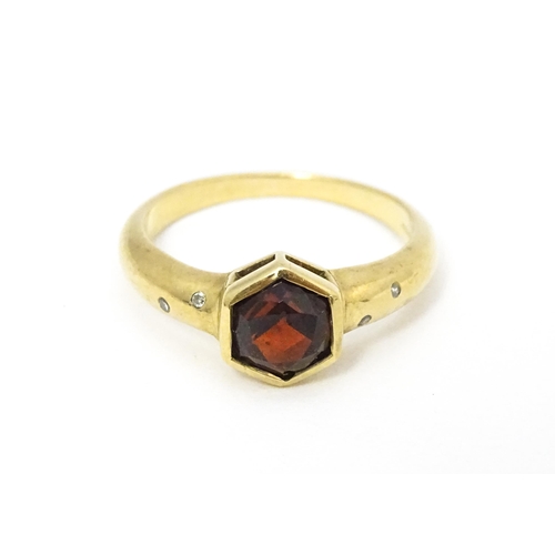 585 - A 9ct gold ring set with central hexagonal garnet flanked by two diamonds to each shoulder Ring size... 