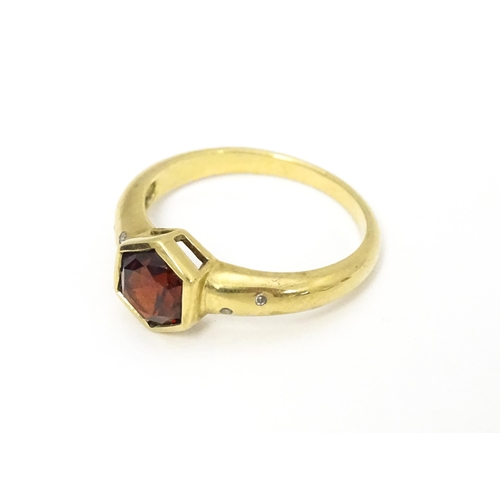 585 - A 9ct gold ring set with central hexagonal garnet flanked by two diamonds to each shoulder Ring size... 