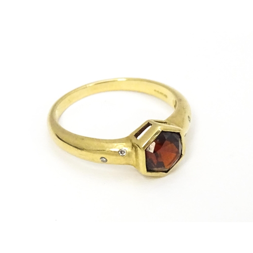 585 - A 9ct gold ring set with central hexagonal garnet flanked by two diamonds to each shoulder Ring size... 