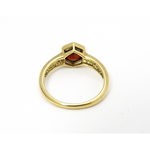 585 - A 9ct gold ring set with central hexagonal garnet flanked by two diamonds to each shoulder Ring size... 