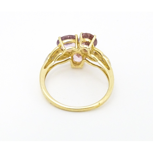 587 - A 10k gold ring set with diamonds and a trio of pink stones. Ring size approx. L