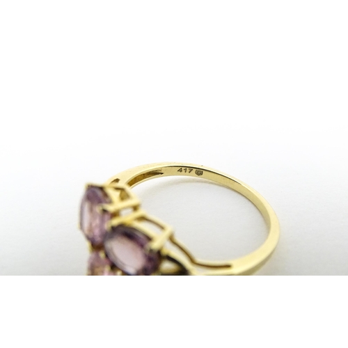 587 - A 10k gold ring set with diamonds and a trio of pink stones. Ring size approx. L