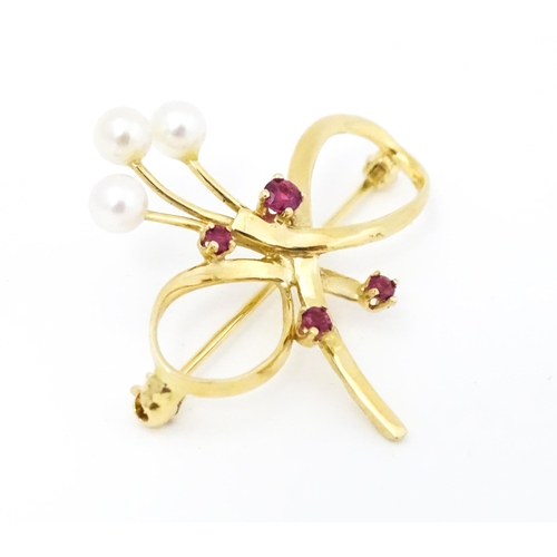 631 - A 10k gold brooch of bow form with pearl and ruby detail. Approx. 1 1/4