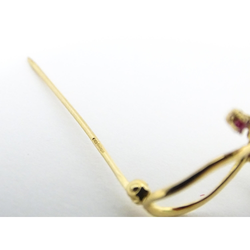 631 - A 10k gold brooch of bow form with pearl and ruby detail. Approx. 1 1/4